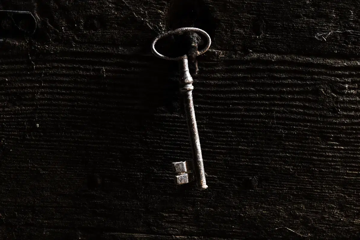 Clé ancienne sur une porte en bois massif – symbole de la transmission d’un bien immobilier et de la confiance accordée à un professionnel de l’immobilier